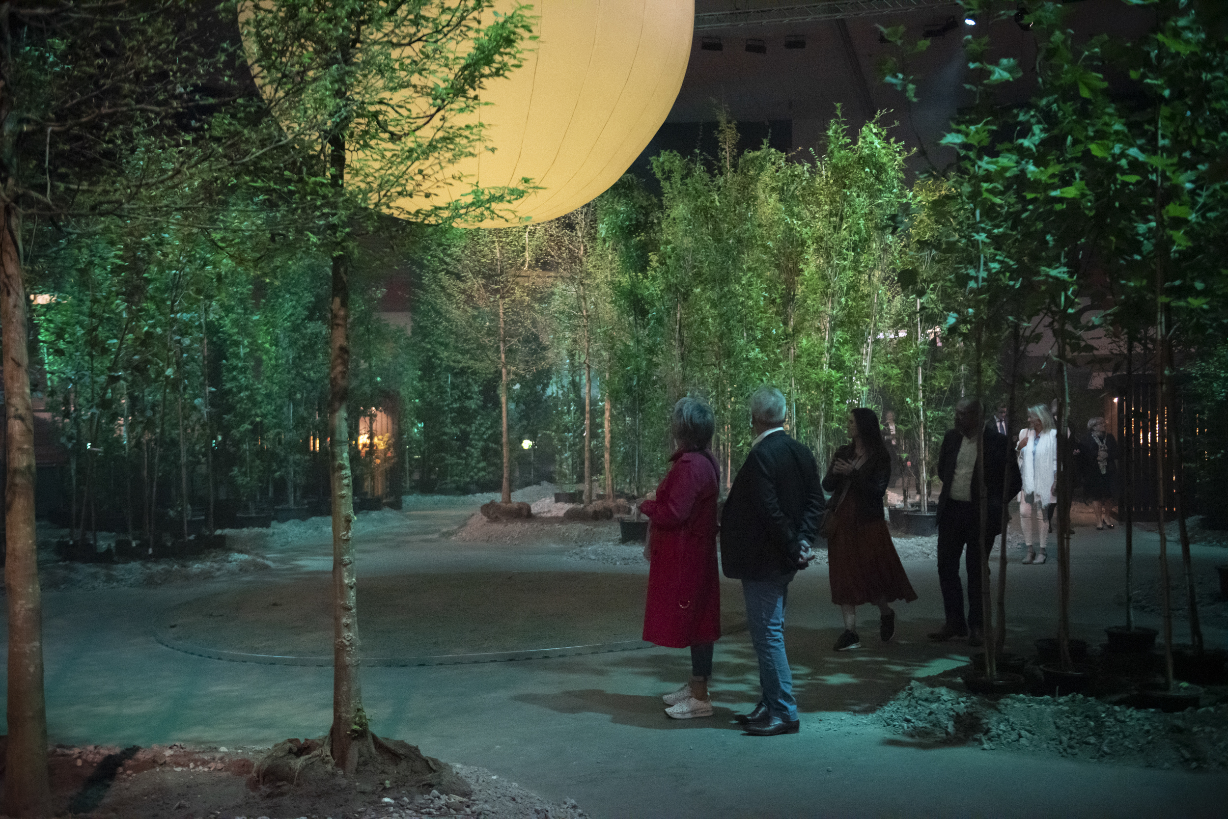 Bezoekers op nocturne Floraliën Gent 2022 in bos met blauwe mist
