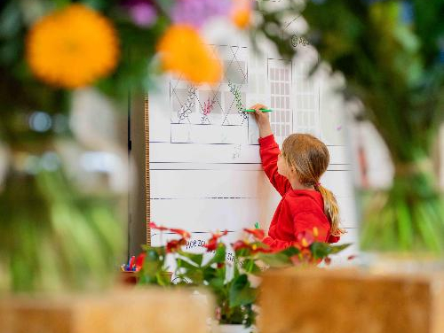 beeld van jong meisje dat op bord tekent omringd door bloemen buiten focus